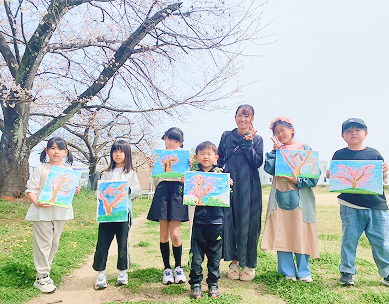 桜の木と桜の絵を持って並ぶ生徒たち